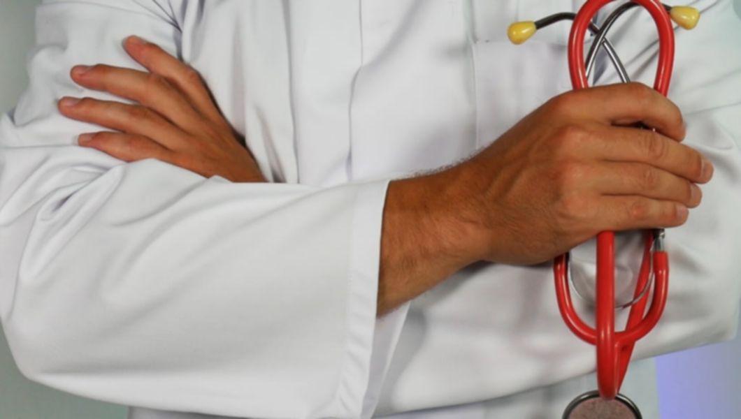 Medic în halat alb, care ține în mână un stetoscop