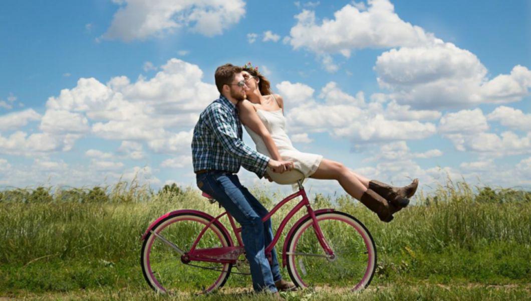 un cuplu, fericiți pe o bicicletă