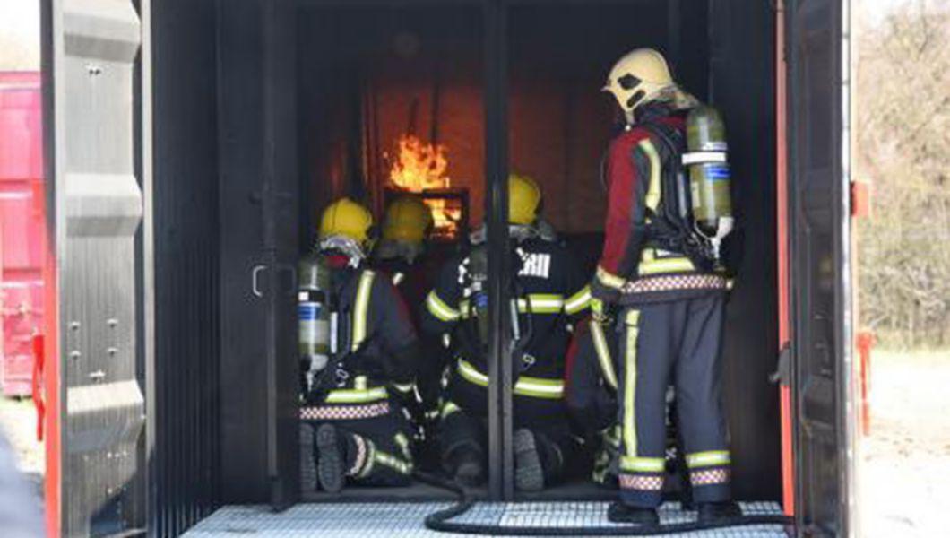 Trei pompieri într-un simulator de incendii mobil