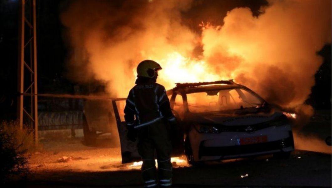 Pompier din Israel lângă o mașină în flăcări