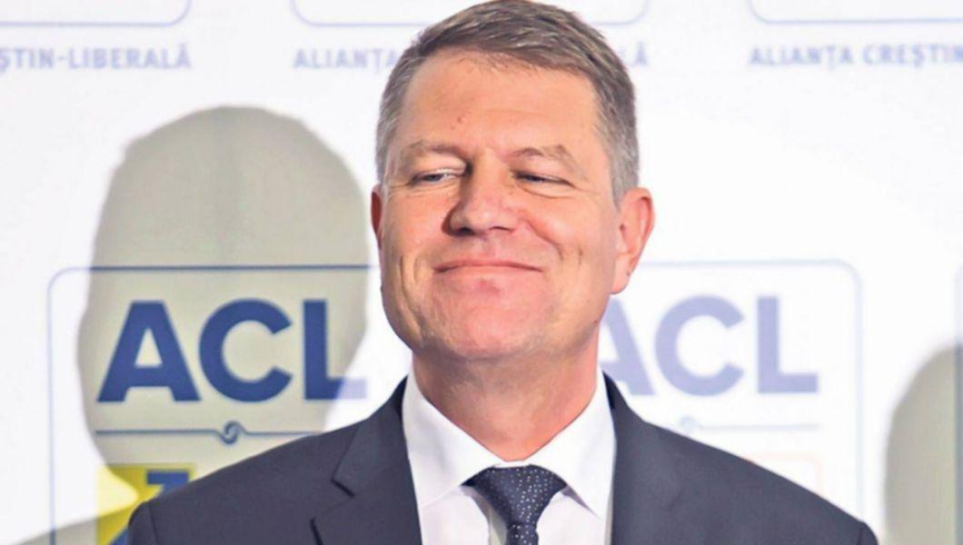 Klaus Iohannis, președintele României zâmbește iar în spatele lui se află un banner cu ACL