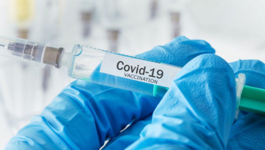 Seringă de vaccin anti-COVID-19, ținută în mână de o asistentă