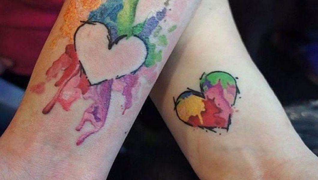 doua maini suprapuse cu tatuaje in forma de inimi colorate