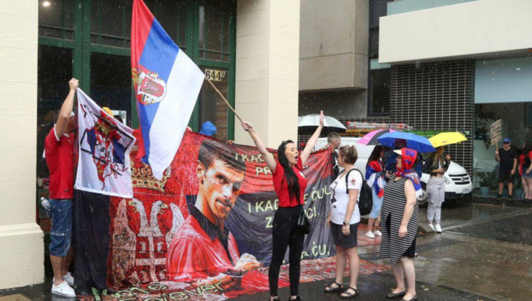 o femeie ține un steag în mână în timpul protestelor de susținere a lui Novak Djokovic din Australia