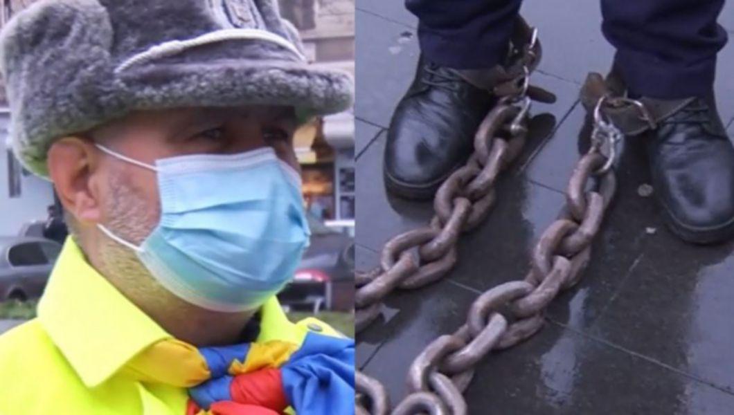 un angajat mai care protestează legat cu lanțuri de picioare