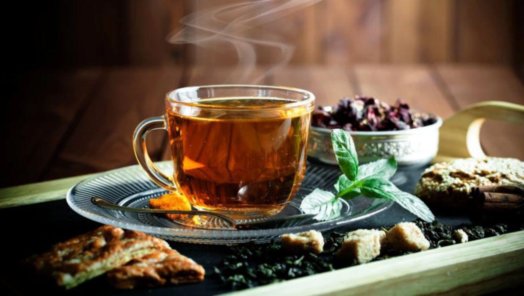 o cana cu ceai si mai multe plante in jurul sau pe o masa