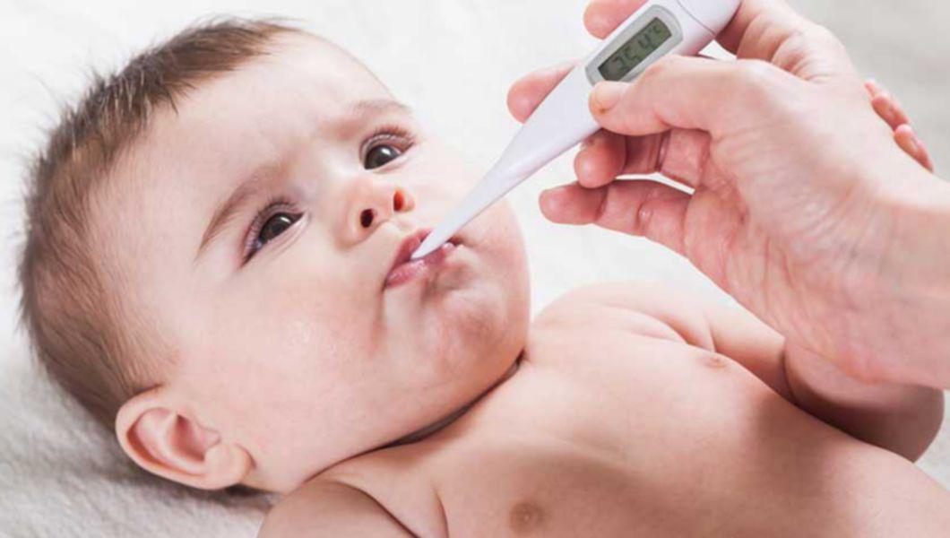 un bebeluș cu termometrul în gură
