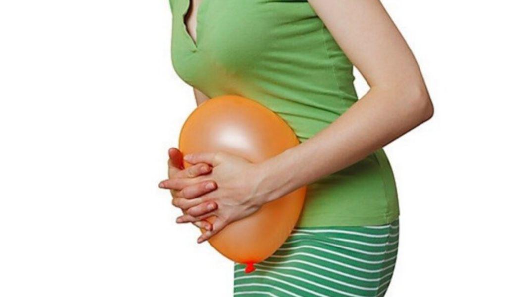 femeie care tine un balon in dreptul abdomenului sau si pune presiune pe el cu mainele