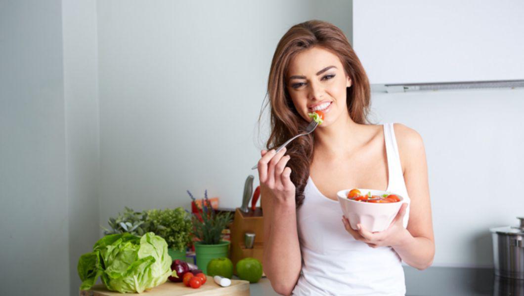 femeie care consuma o salata si tine in mana un bol