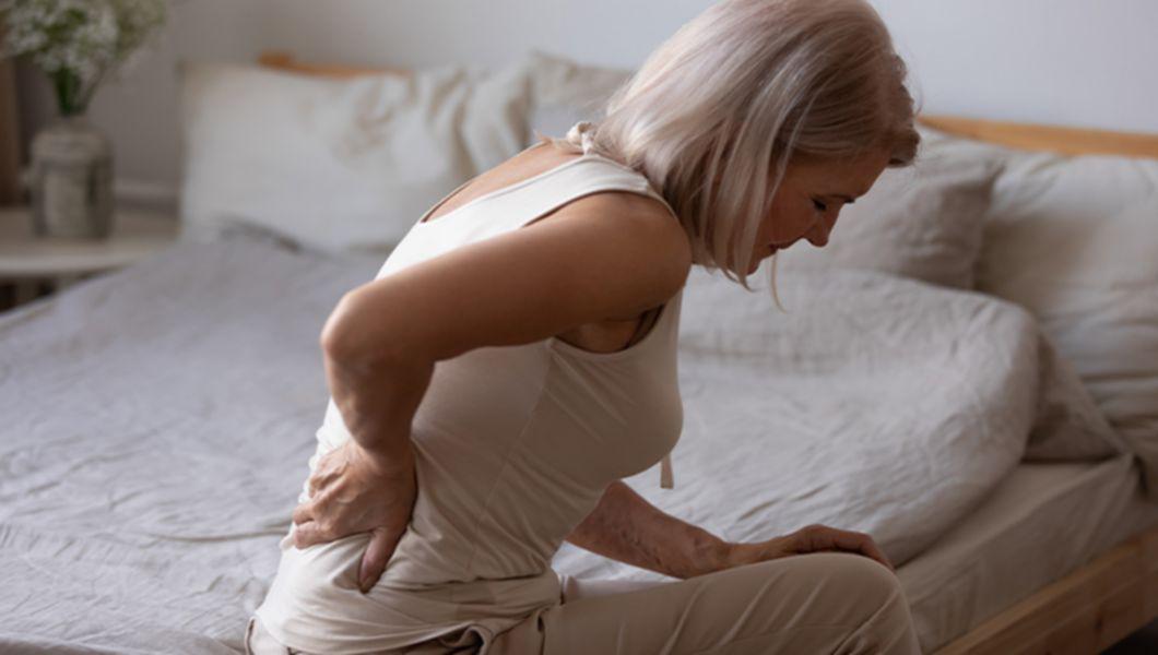 o femeie blondă care se confruntă cu durere de spate