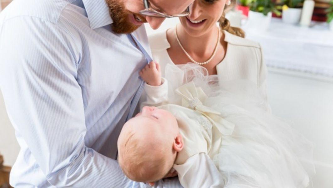 pereche de nasi care tin in brate un bebelus in timpul botezului