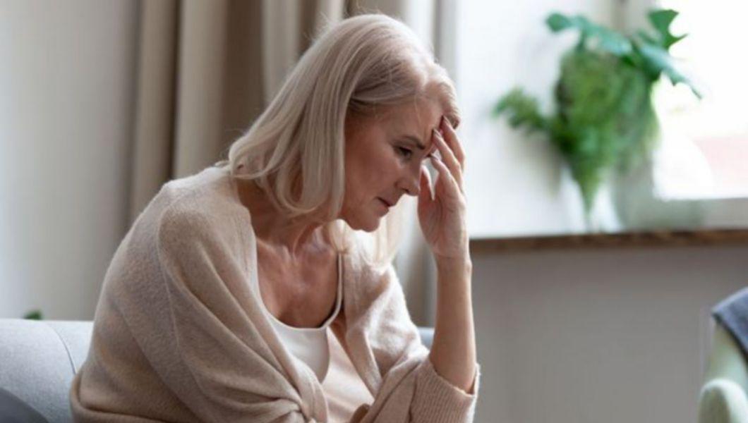 femeie care se tine de cap din cauza durerilor provocate de menopauza