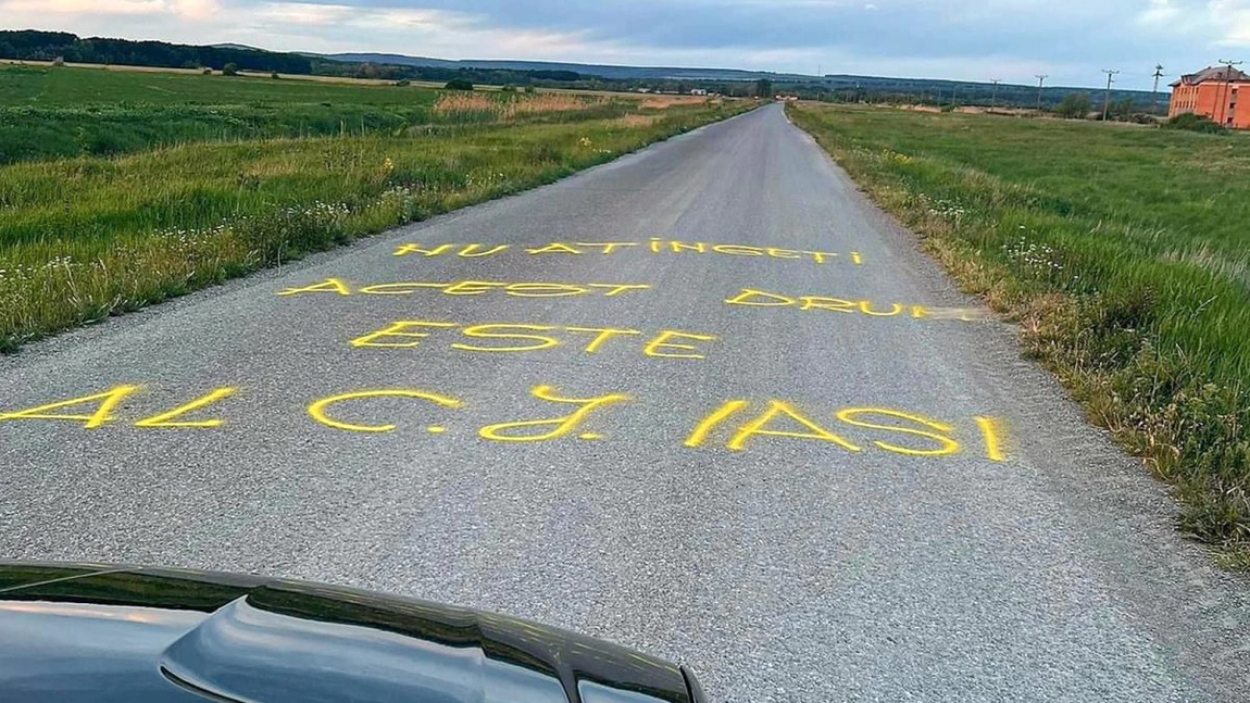 Sătui de drumul impracticabil, sătenii dintr-o comună din județul Iași au scris un mesaj direct pe asfalt: „Atenție, gropi. Acest drum este al CJ Iași” - FOTO