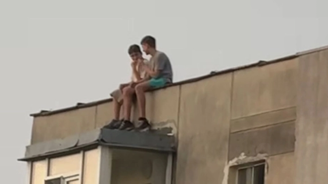 Inconștiență dusă la extrem. Doi copii au fost fotografiați pe acoperișul unui bloc de 10 etaje din Alexandru cel Bun. Au picioarele pe exterior