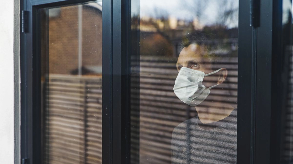 Man with mask looking out of window