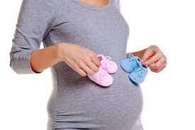 femeie însărcinată care ține n mână niște botoșei albaștri și botoșei roz