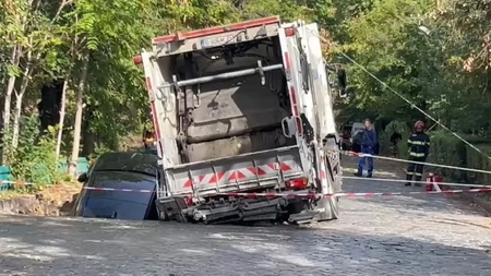 O mașină care aparține unei femei a căzut într-o groapă formată după ce asfaltul străzii s-a surpat. Momentul, surprins de o cameră