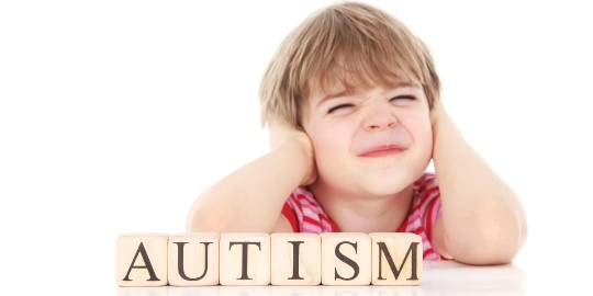 un copil cu autism care isi tine mainile pe urechi