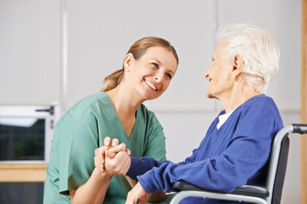 o asistentă care ține de mână o femeie în vârstă