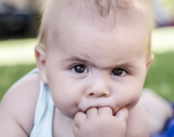 un bebeluș nervos cu degetele în gură