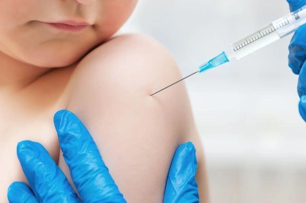 Un medic administreaza un vaccin unui copil