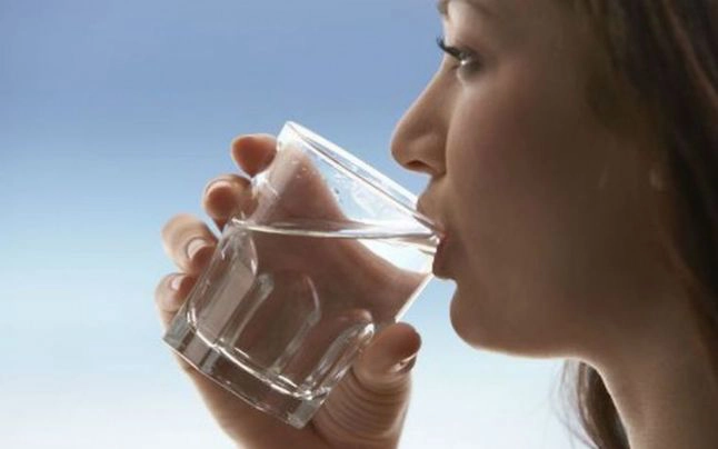 o femeie care bea un pahar cu apă