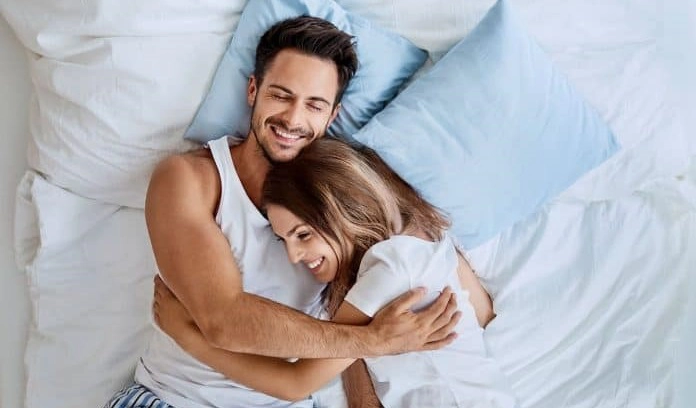 un cuplu fericit care se îmbrățișează în pat