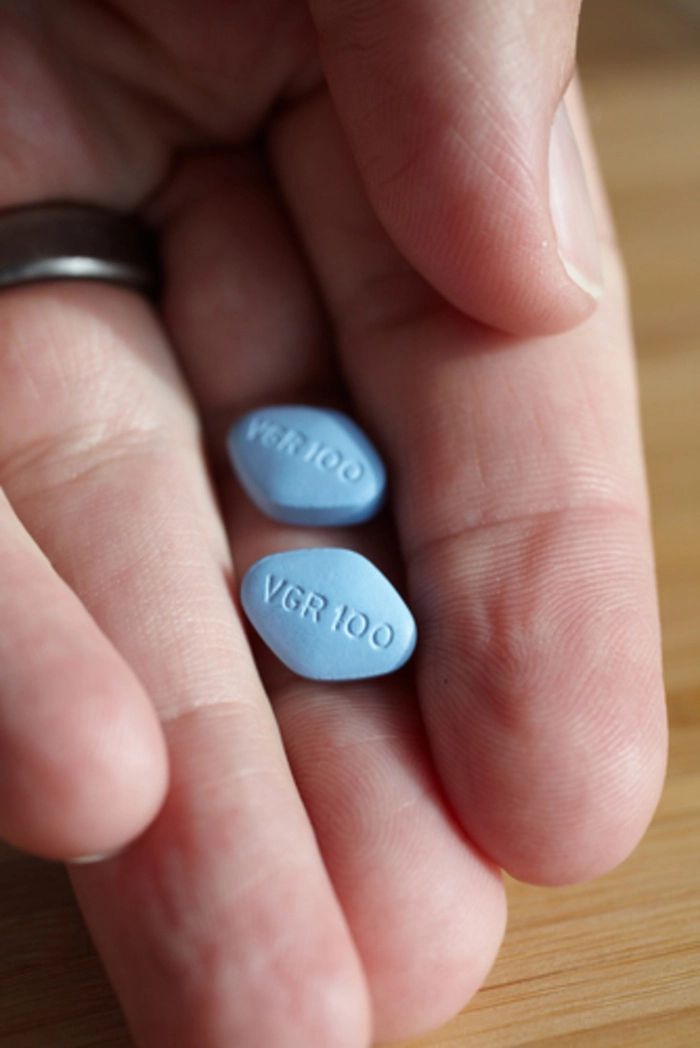 persoana care tine in mana doua pastile de viagra
