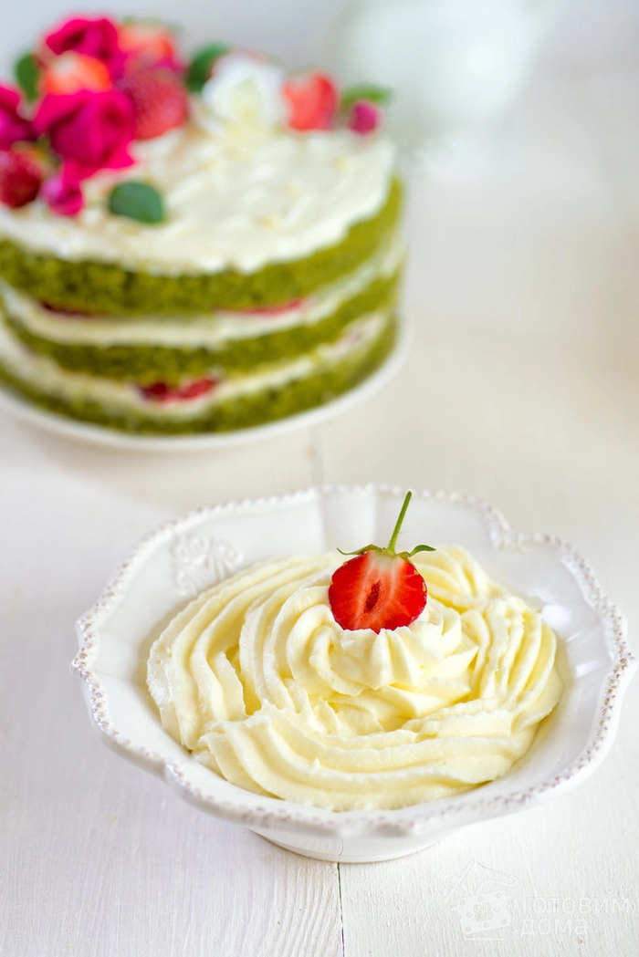 un bol cu crema de mascarpone cu o capsuna langa un tort