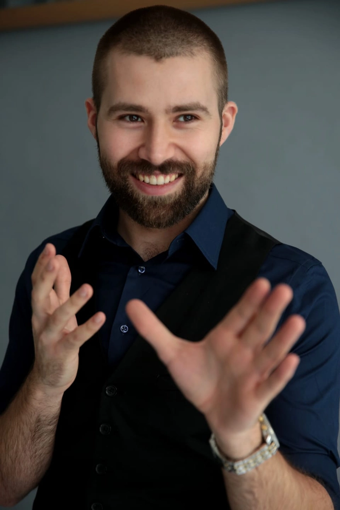 Adrian Munteanu imbracat cu camasa si vesta rade si gesticuleaza
