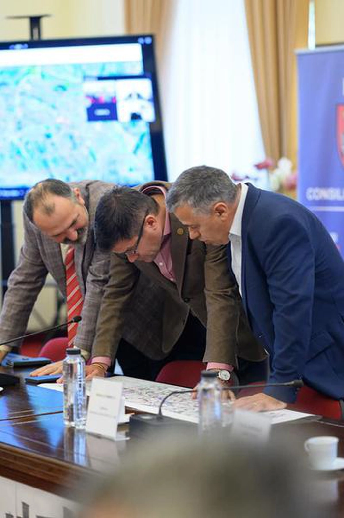  persoane ce se uita pe o harta si vorbesc