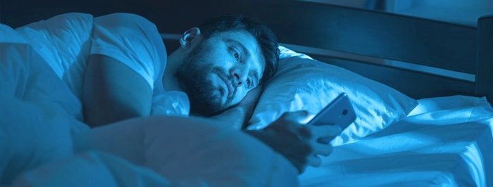 persoana care sufera de insomnie si se uita pe telefon