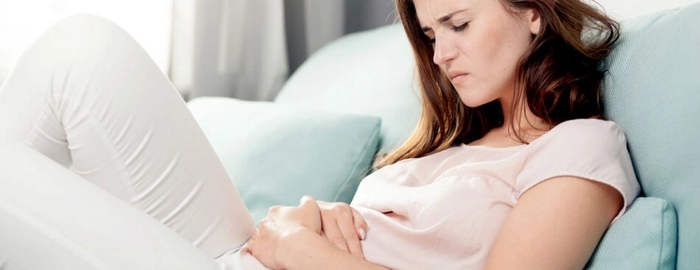 femeie care se tine de abdomen din cauza infectiei urinare