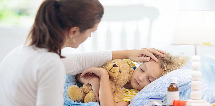 un copil răcit vegheat de mama lui
