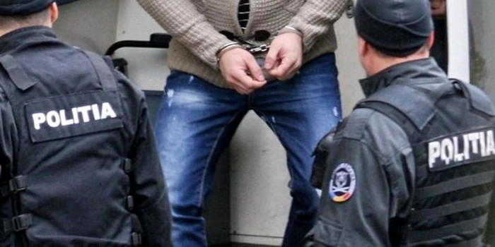 Un barbat incatusat in prezenta a doi barbati imbracati in uniforma de politisti