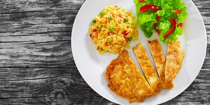 snitel de porc cu orez si salata pe o farfurie