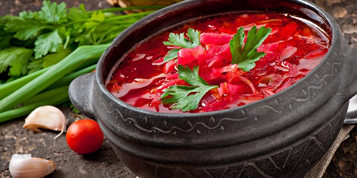un bol cu ciorba de legume pe o masa langa mai multe legume proaspete