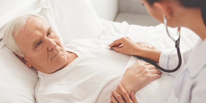 doctor care asculta cu un stetoscop inima unui barbat culcat pe un pat de spital