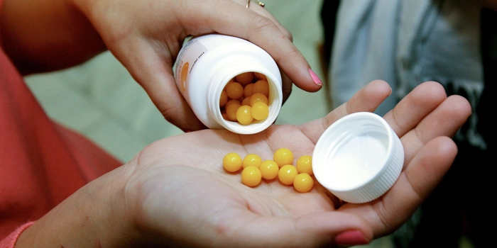 o persoana care isi toarna vitamine in palma dintr-un recipient