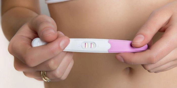 femeie care tine in mana un test de sarcina