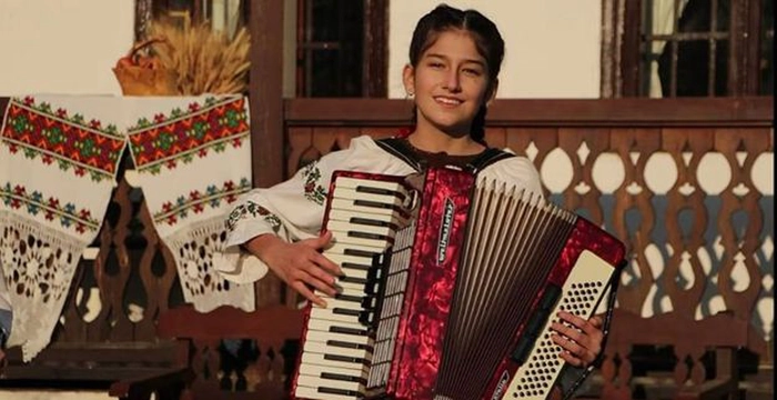  O persoana cu un acordeon, in fata unei case