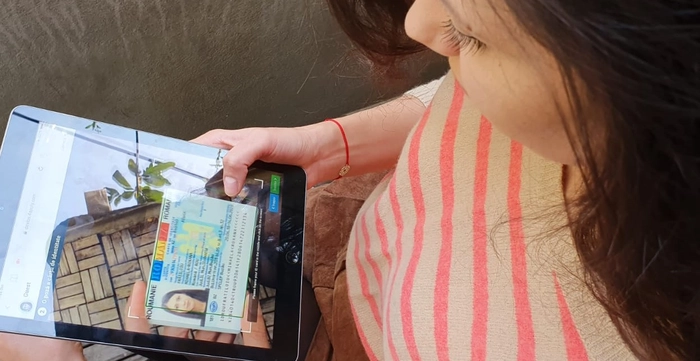 o persoana de gen feminin isi fotografiaza cartea de identitate cu ajutorul unei tablete