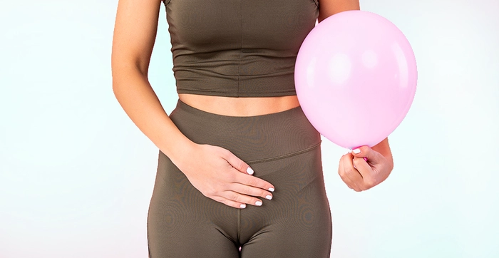 femeie care se tine de burta si in alta mana tine un balon roz