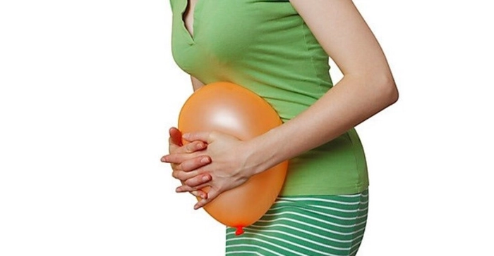 femeie care se tine de burta si are un balon in mana