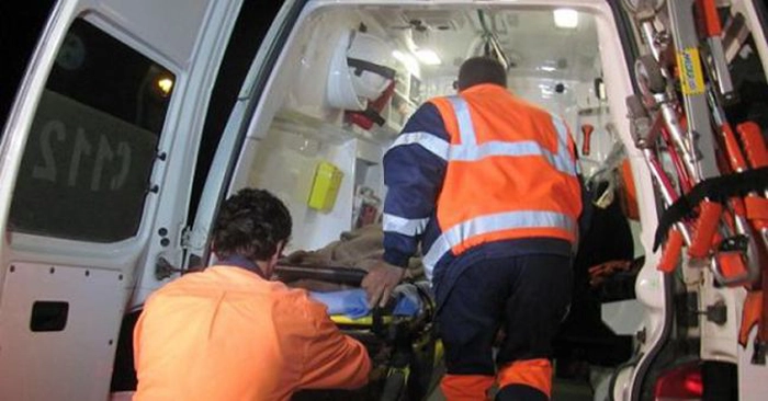 doua persoane de gen masculin ridica o targa cu un pacient intr-o masina de ambulanta