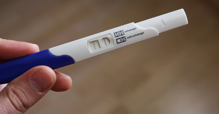 femeie care tine in mana un test de sarcina