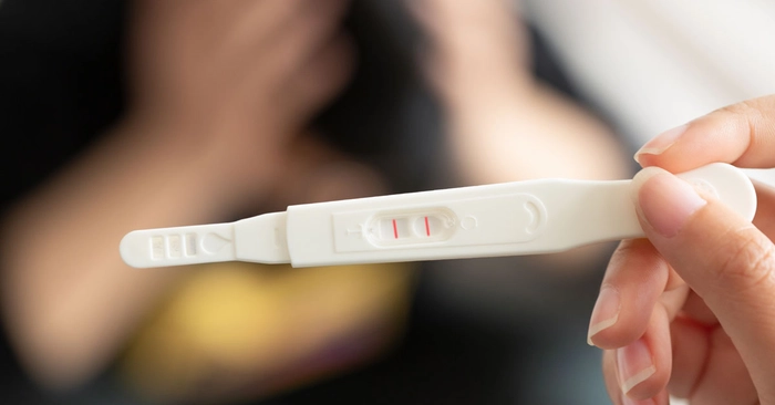 femeie care tine in mana un test de sarcina