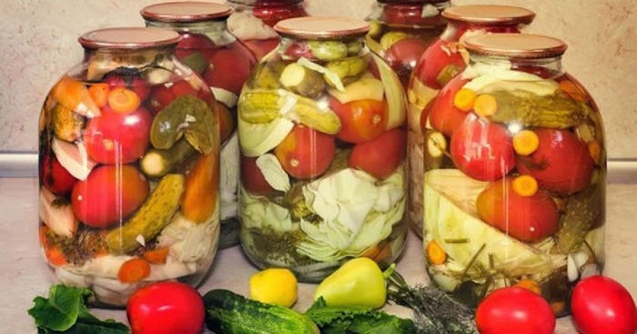 mai multe borcane cu muraturi asortate pe o masa langa legume proaspete