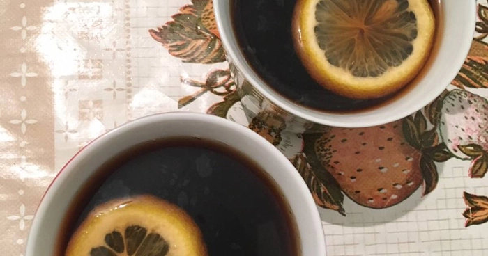 doua cesti de cafea cu lamaie pe o masa