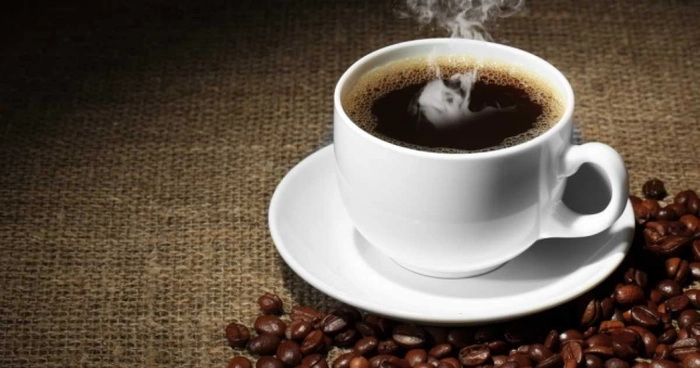 ceasca de cafea prezentata alaturi de boabe de cafea